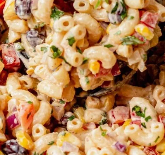 Bowl of colorful Mexican macaroni salad with fresh vegetables and lime dressing.