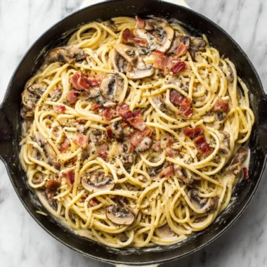 A delicious plate of creamy bacon mushroom pasta garnished with herbs.