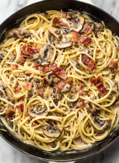 A delicious plate of creamy bacon mushroom pasta garnished with herbs.