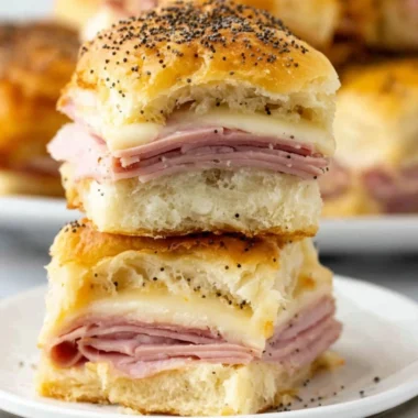 Baked ham and cheese sliders on a platter, topped with sesame seeds