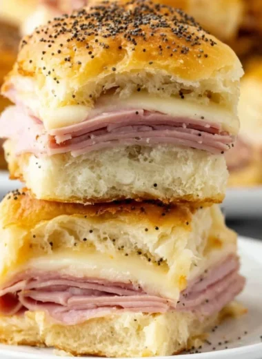 Baked ham and cheese sliders on a platter, topped with sesame seeds
