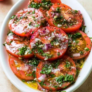 Delicious marinated tomatoes in a bowl, garnished with herbs and spices.