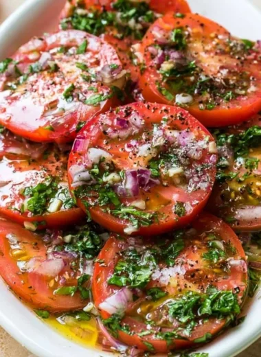 Delicious marinated tomatoes in a bowl, garnished with herbs and spices.