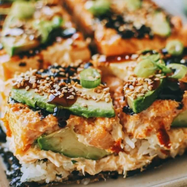 Baked spicy salmon sushi casserole in a ceramic dish garnished with green onions