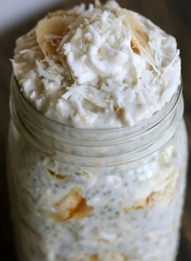 Healthy Banana and Coconut Overnight Oats in a glass bowl with toppings.