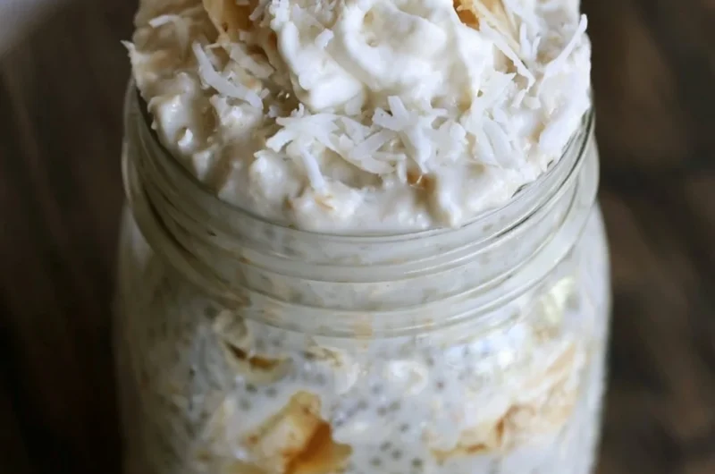 Healthy Banana and Coconut Overnight Oats in a glass bowl with toppings.