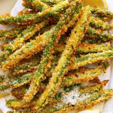 Crispy breaded air fryer asparagus served on a white plate.