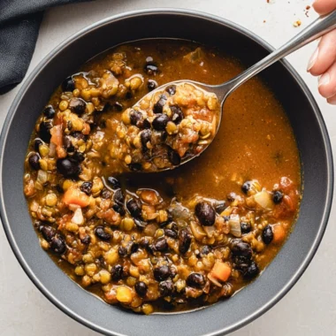 Bowl of protein-packed black bean and lentil soup topped with fresh herbs.