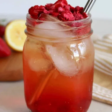 A refreshing glass of iced strawberry green tea with fresh strawberries