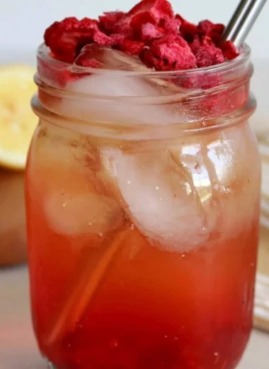 A refreshing glass of iced strawberry green tea with fresh strawberries