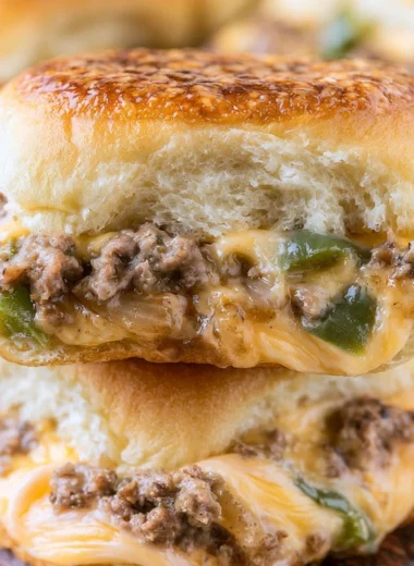 Philly Cheesesteak Sliders topped with melted cheese and sautéed onions
