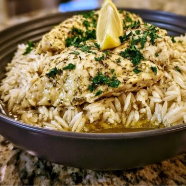 Plate of slow cooker lemon herb chicken and rice garnished with fresh herbs.