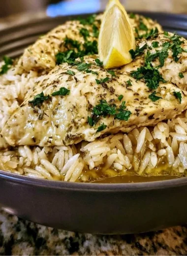 Plate of slow cooker lemon herb chicken and rice garnished with fresh herbs.