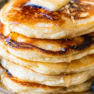 Plate of creamy ricotta pancakes topped with berries and syrup