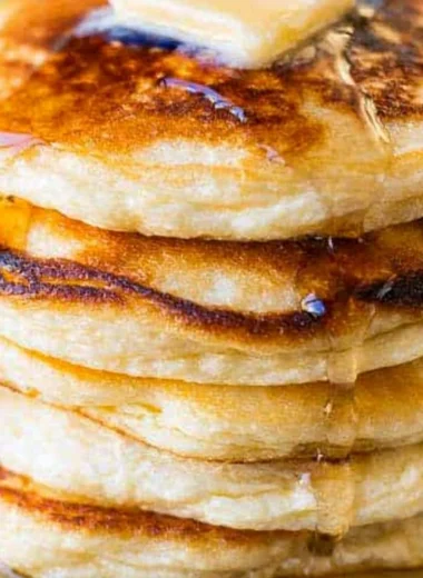 Plate of creamy ricotta pancakes topped with berries and syrup